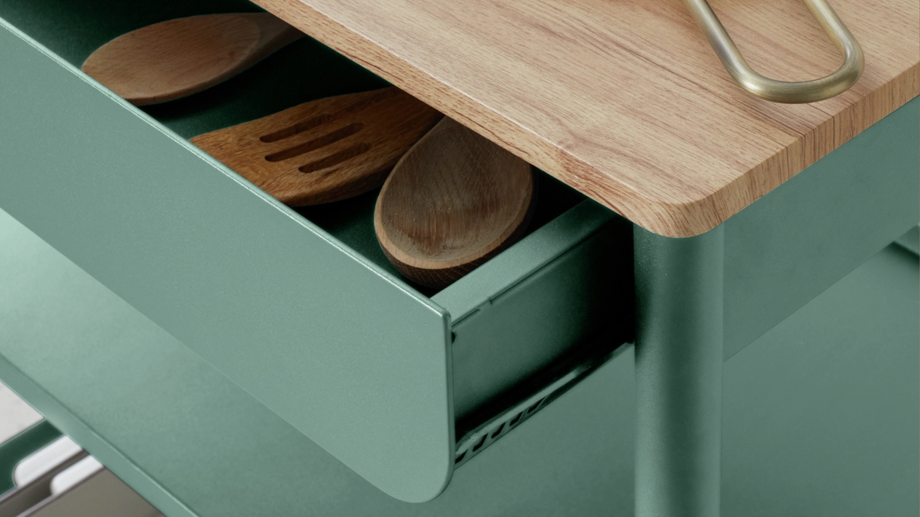 close up of a teal kitchen island with spoons in a drawer