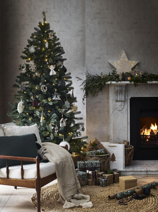 natural Christmas with wooden decorations, garland on mantlepiece, armchair, kraft wrap presents, log burner