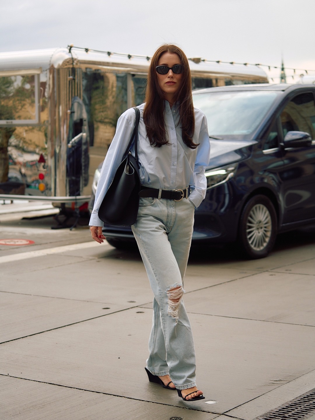 Annabel wears a blue shirt with ripped jeans and wedges