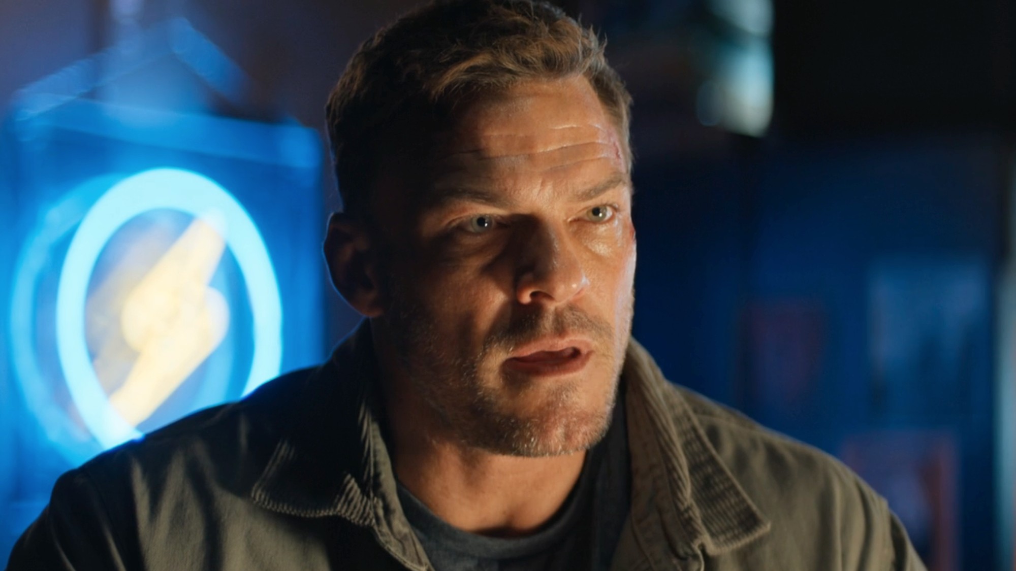 Alan Ritchson as Reacher looking concerned in Reacher. 