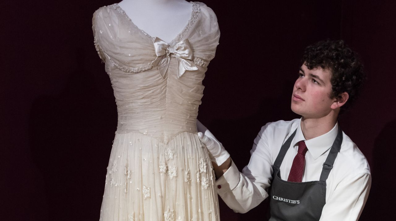 Art technician adjusts a royal bridesmaid&#039;s dress by Norman Hartnell, 1947 from the Wedding of H.M. Queen Elizabeth II and H.R.H. The Duke of Edinburgh (estimate: £30,000-50,000), the only one of the bridesmaids dresses to come to the market, it was worn by the late Lady Elizabeth Longman.