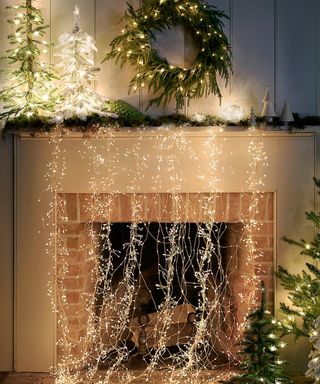Christmas fireplace styling with cascading stargazer lights and evergreen foliage