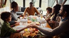 Family members hold hands around the dinner table and say a prayer.