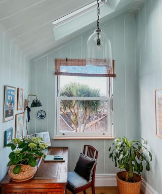 A light blue home office with wallpaper and a skylight