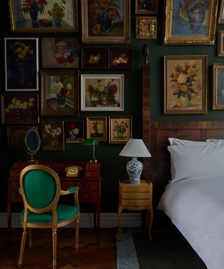 vintage style dark green amsterdam hotel bedroom with a large antique gallery wall of flower paintings in homage to the dutch location