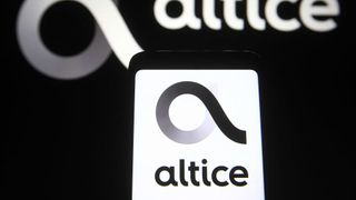 The Altice logo is shown on a phone, while an out of focus version of the same logo shows in white on a wall
