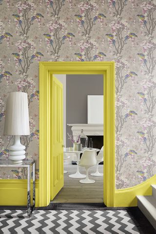 grey floral wallpaper and grey and white chevron rug in hallway with yellow skirting and doors as a n example of how to use pattern and prints and interiors by little greene