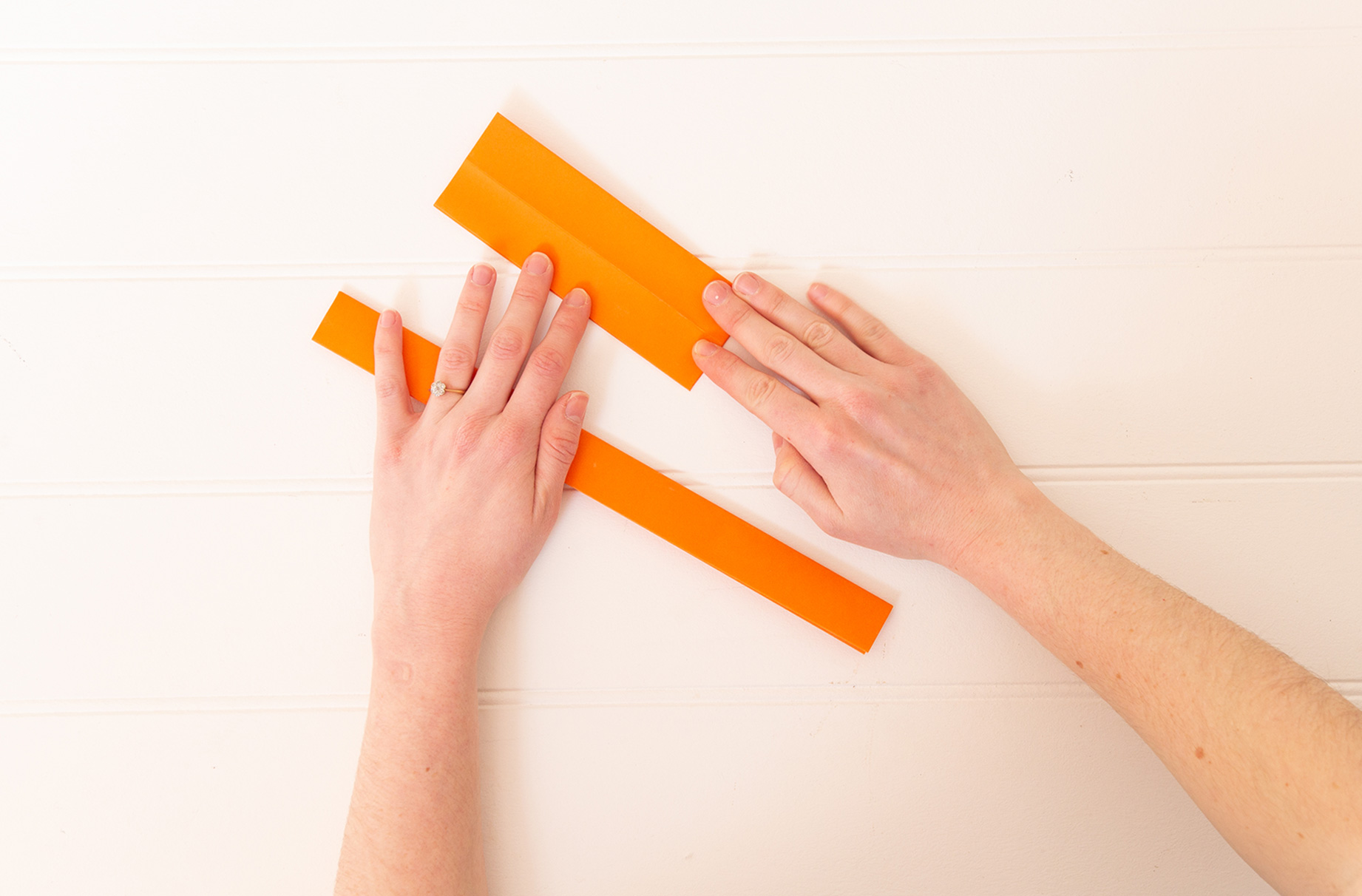 A woman's hands folding orange paper.
