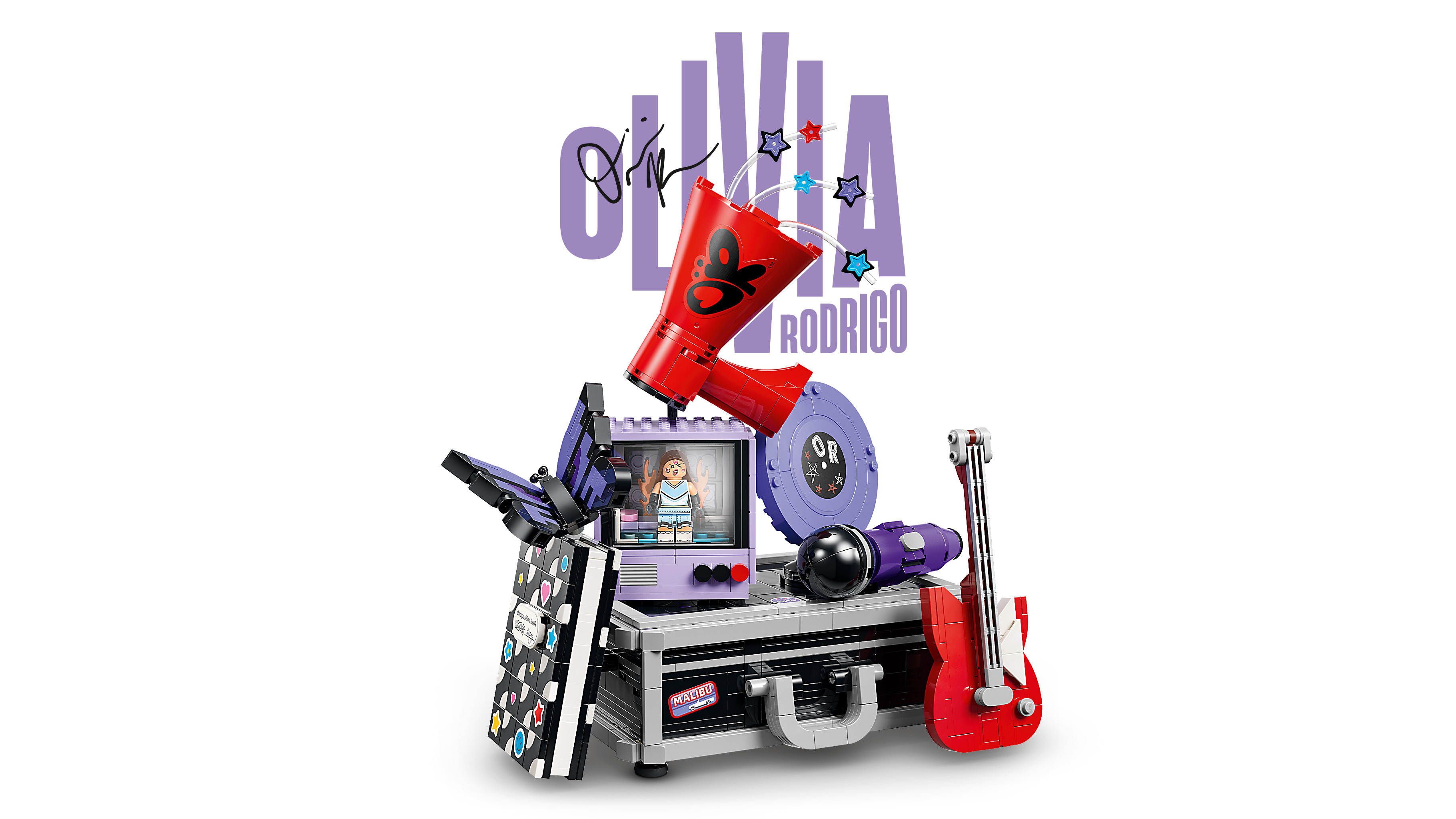 Product shot of the Lego Secret Storage set against a white background, featuring a red megaphone, vinyl disc, notebook, microphone and red guitar built onto a silver case, with the Olivia Rodrigo logo above.