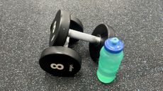 Two dumbbells and water bottle on a gym floor