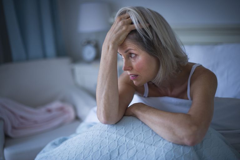 woman sitting up in bed at at night