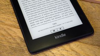 The bottom half of a Kindle Paperwhite on a wooden surface