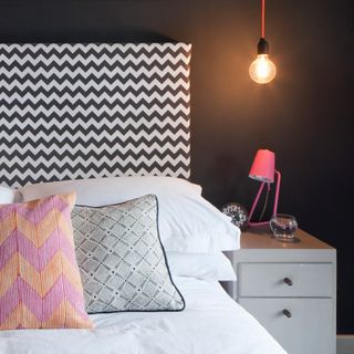 bed with graphic print headboard and two bedside lamps