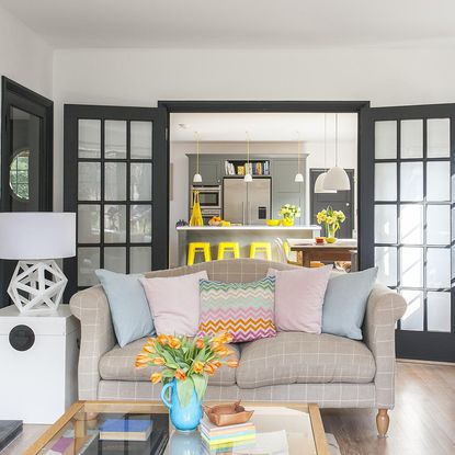 living room with wooden flooring and sofa set with colourful cushions