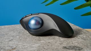 A black Logitech Ergo M575 ergonomic mouse with a teal trackball on the left side