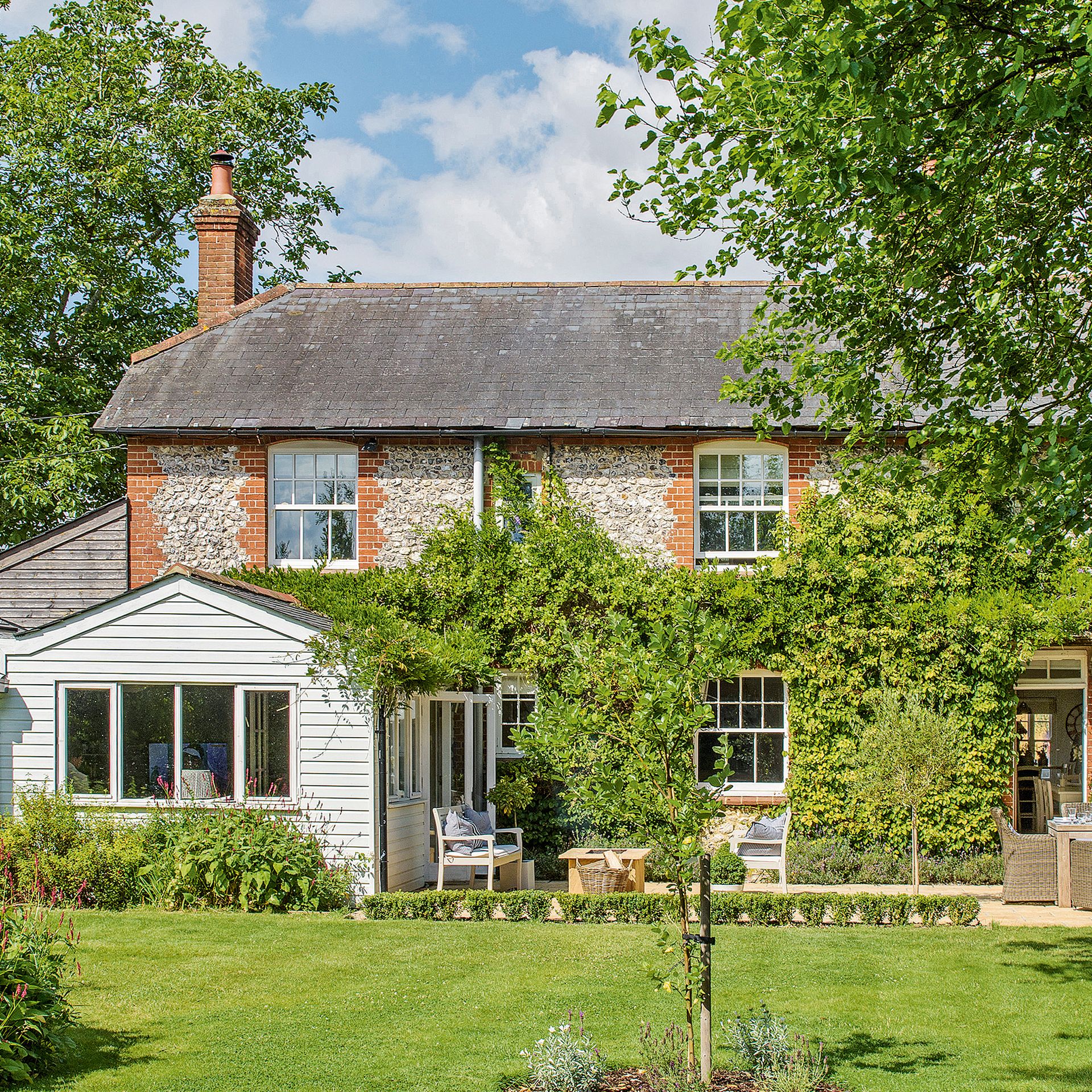 Rear exterior of a country cottage with flint walls and a slate roof