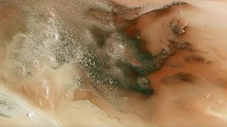 A satellite view of a landscape with swirling brown, red, and green shapes