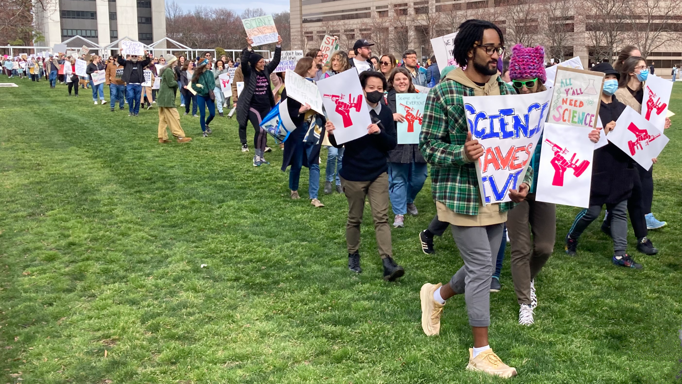 Bidikan poster dan pemrotes di Stand Up For Science Rally di Raleigh