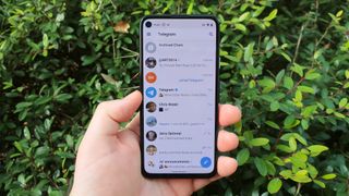 Telegram home screen on an Android phone held in one hand outdoors in the day time.