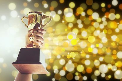 Hand Holding Trophy Against Defocused Lights