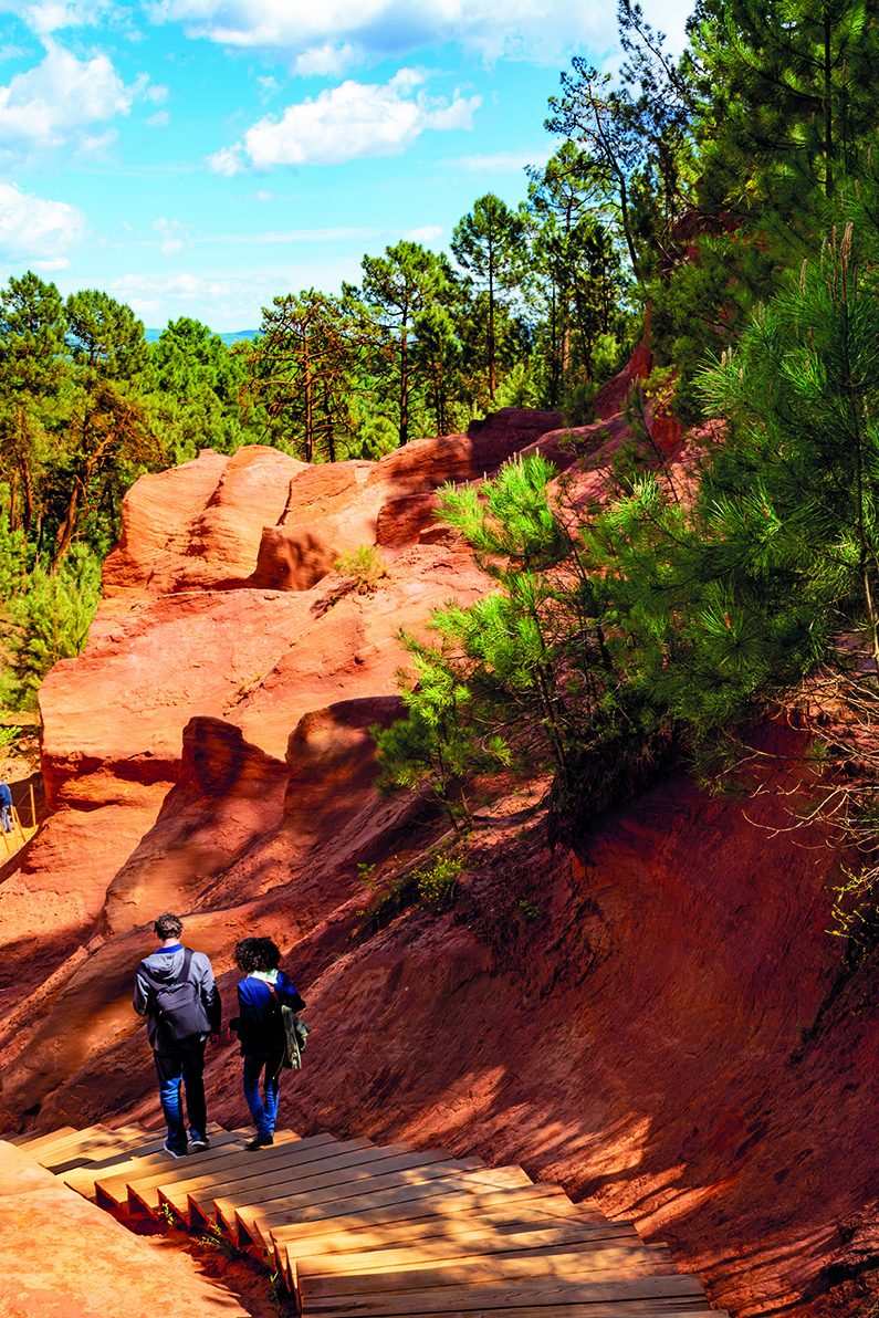 two peolpe walking down a track flanked by rocks