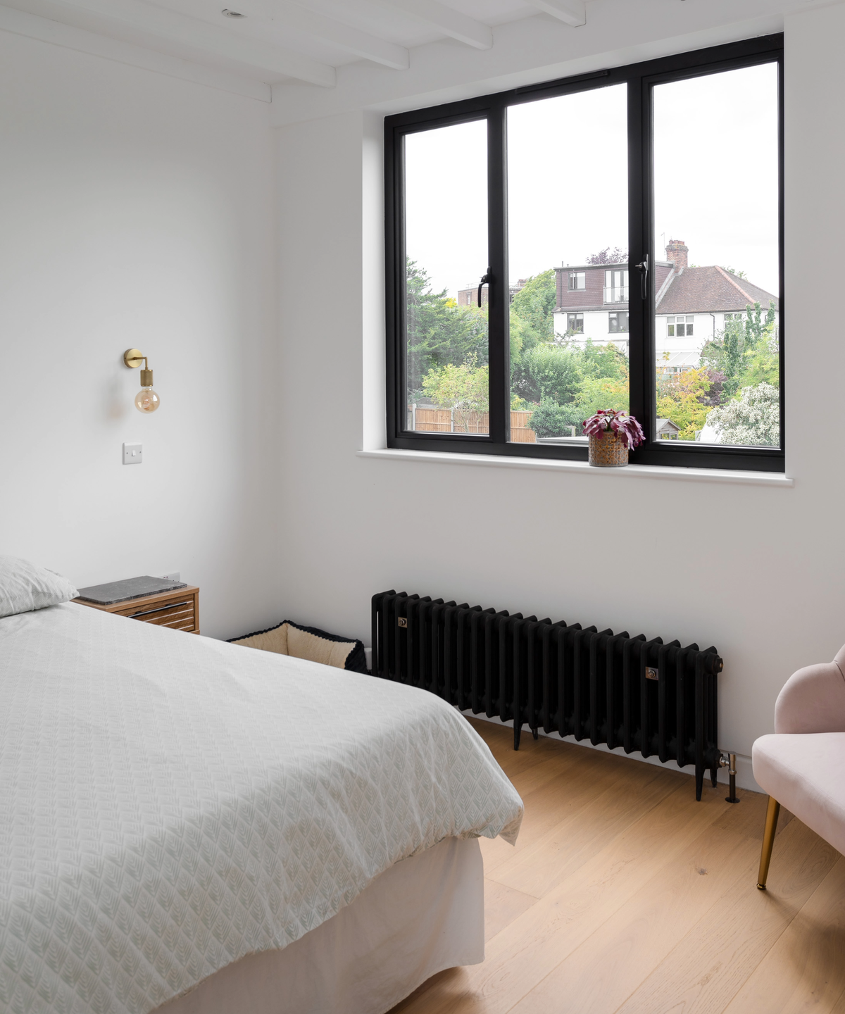 Inside the bedroom, featuring a large black frame window and matching radiator