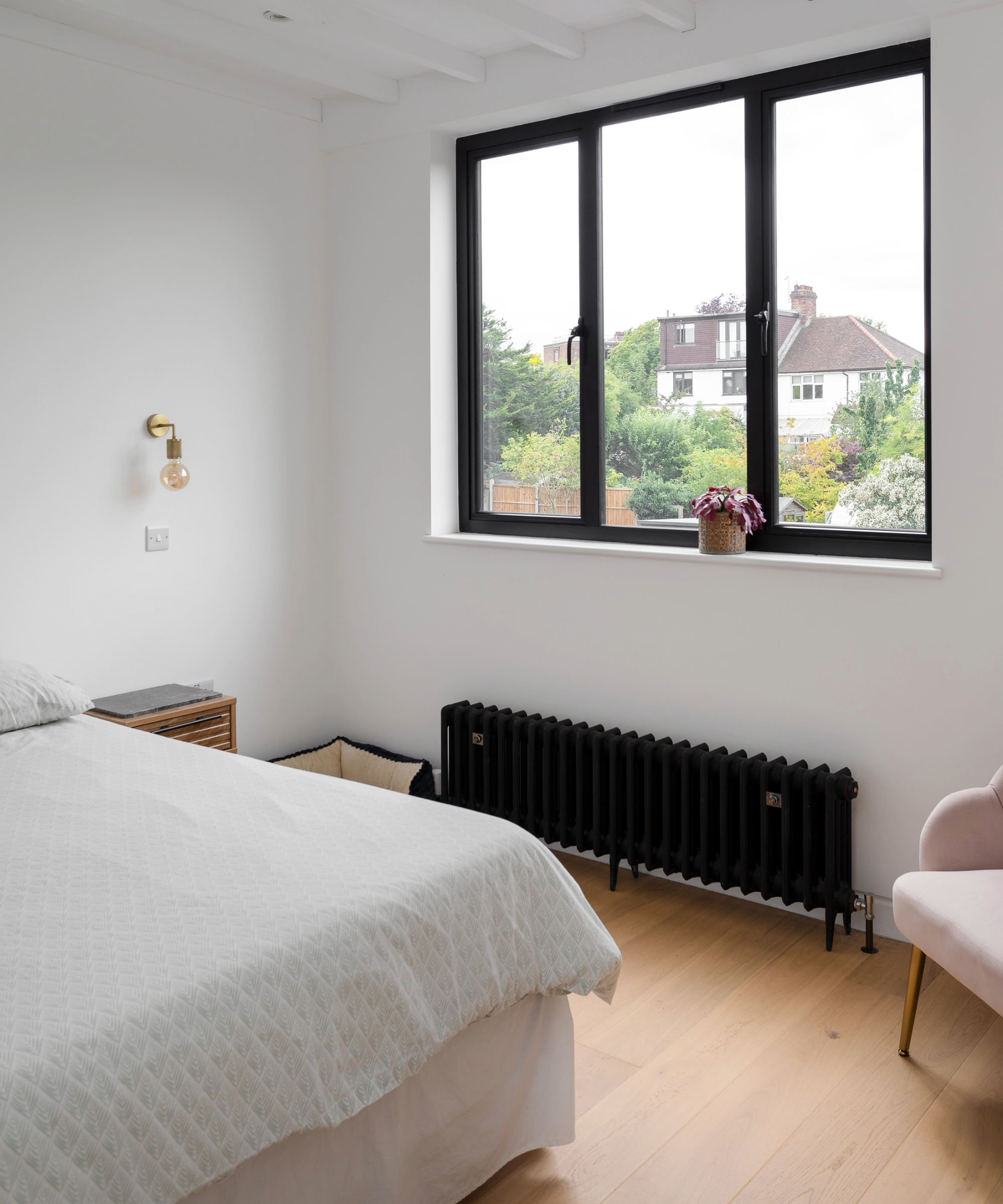 Inside the bedroom, featuring a large black frame window and matching radiator