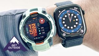 Close-up a user's wrist wearing both the Garmin Instinct 3 in teal and Apple Watch Series 10 on a blue band