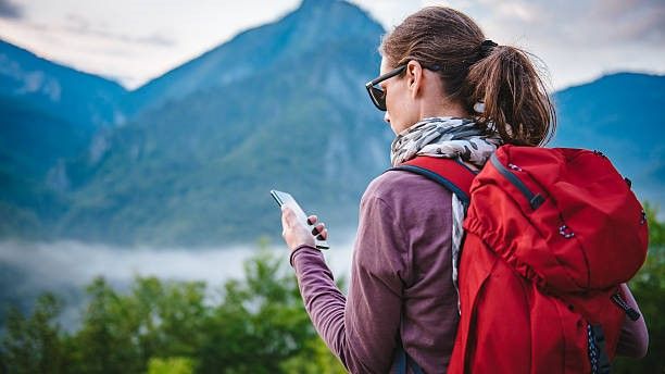 A hiker looking at her phone in the mountains