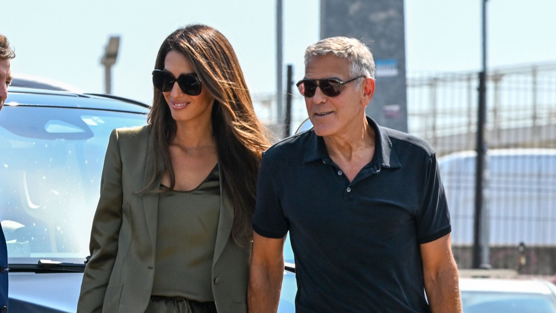 An image of Amal Clooney wearing an olive green pair of satin shorts and black heels whilst arriving at the Venice airport. 