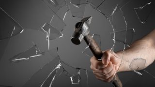 A man breaking window with hammer on dark grey background