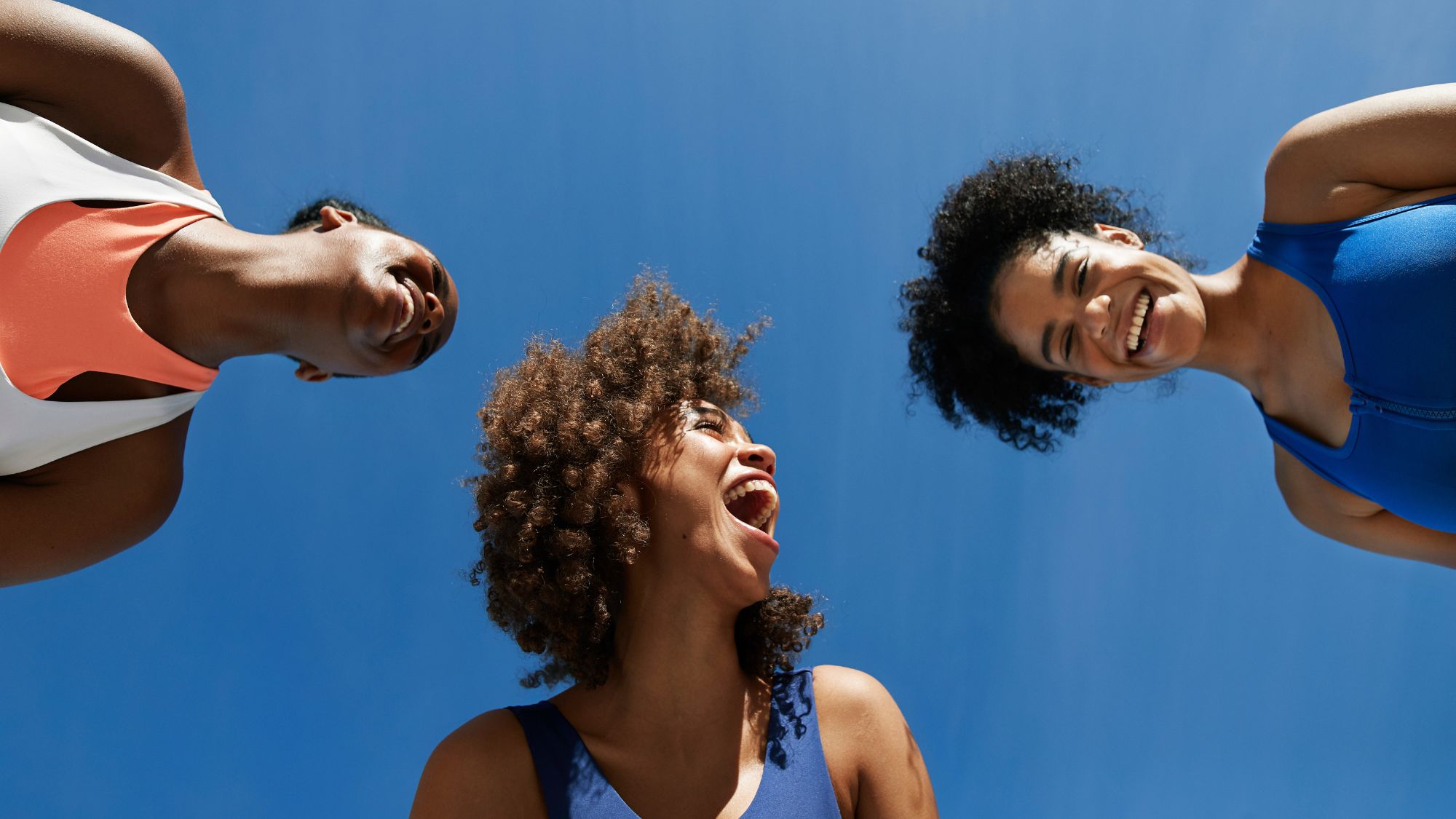 How to find joy: Three women smiling against a blue sky background