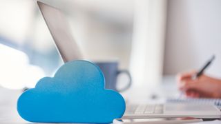 person working on laptop at desk next to cloud symbol