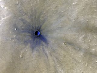 NASA's Mars Reconnaissance Orbiter has spotted a relatively fresh crater on the Red Planet using its High Resolution Imaging Science Experiment (HiRISE) camera. While lower-resolution images can help scientists identify craters on the Martian surface, high-resolution images like this one can help them determine the age of a crater. For example, radial features known as "rays," which streak outward from the center of a crater, indicate that a crater is relatively young, because these features typically erode over time. A so-called "ejecta blanket" of dark basaltic rock, shown here in blue, creates a splash-like pattern closer to the site of the impact. NASA estimates that this crater, located in Valles Marineris, was created sometime between February and July of 2005.