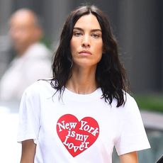 Alexa Chung wearing a denim button skirt, graphic white T-shirt, and burgundy knee-high boots in NYC 