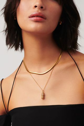woman wearing ridged gold pendant with message inside
