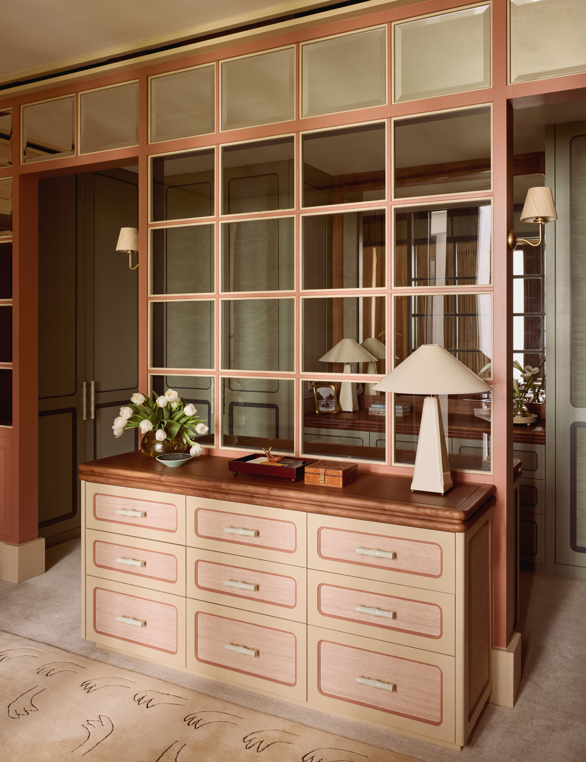 Windowpane-accented dresser inside of a cozy neutral dressing room area, styled alongside a beige table lamp and various collected objects