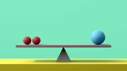 two small red balls and one large blue ball balancing on seesaw