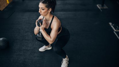 Woman holding a dumbbell goblet squat