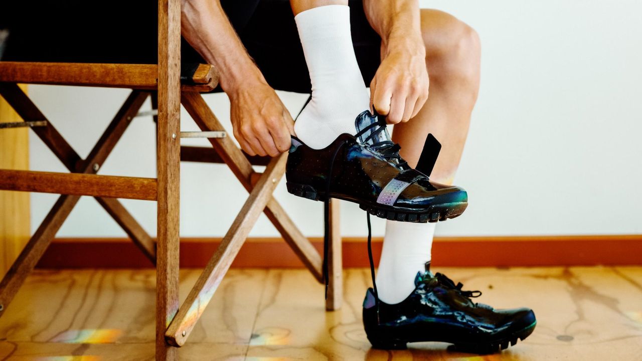 Person putting on the Rapha Explore Shoes while sitting on a chair