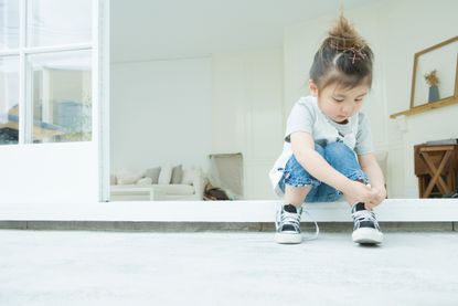 Girl learning to tie her best kids trainers