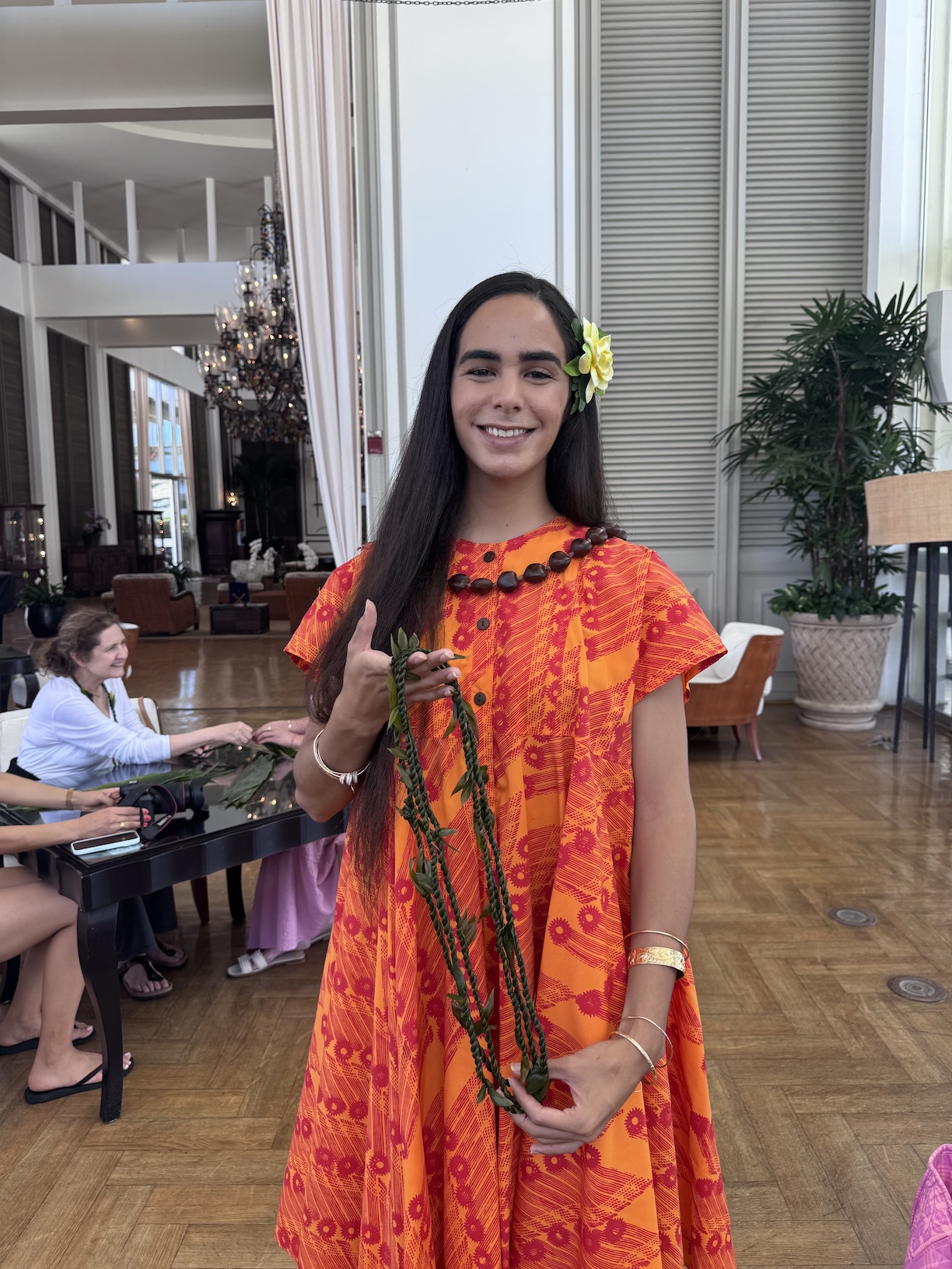 A woman in an orange dress holding leis