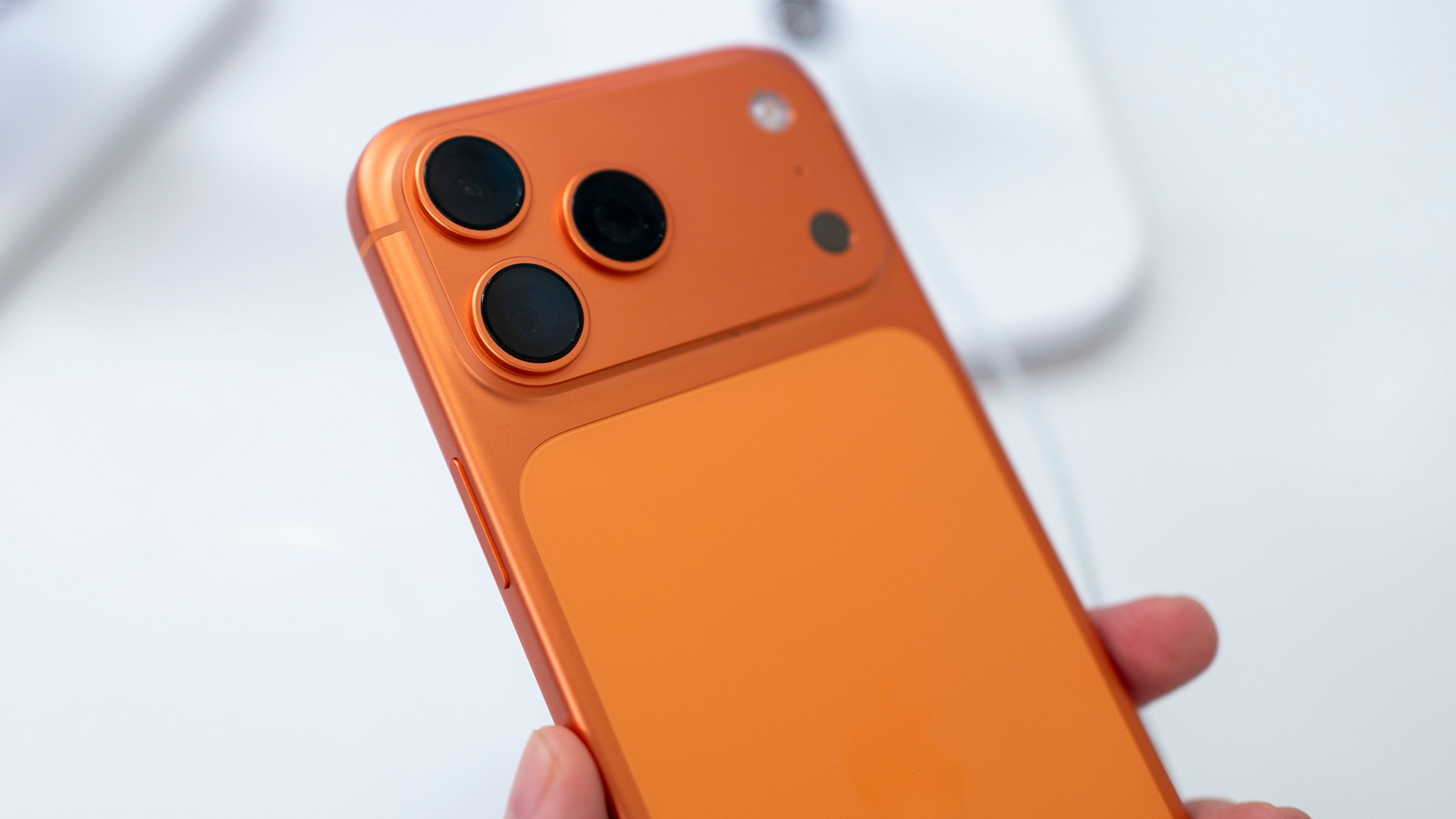 An orange iPhone 17 Pro being held against a white background.