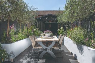 An outdoor dining area with tall paneled borders with trees and a building in the background