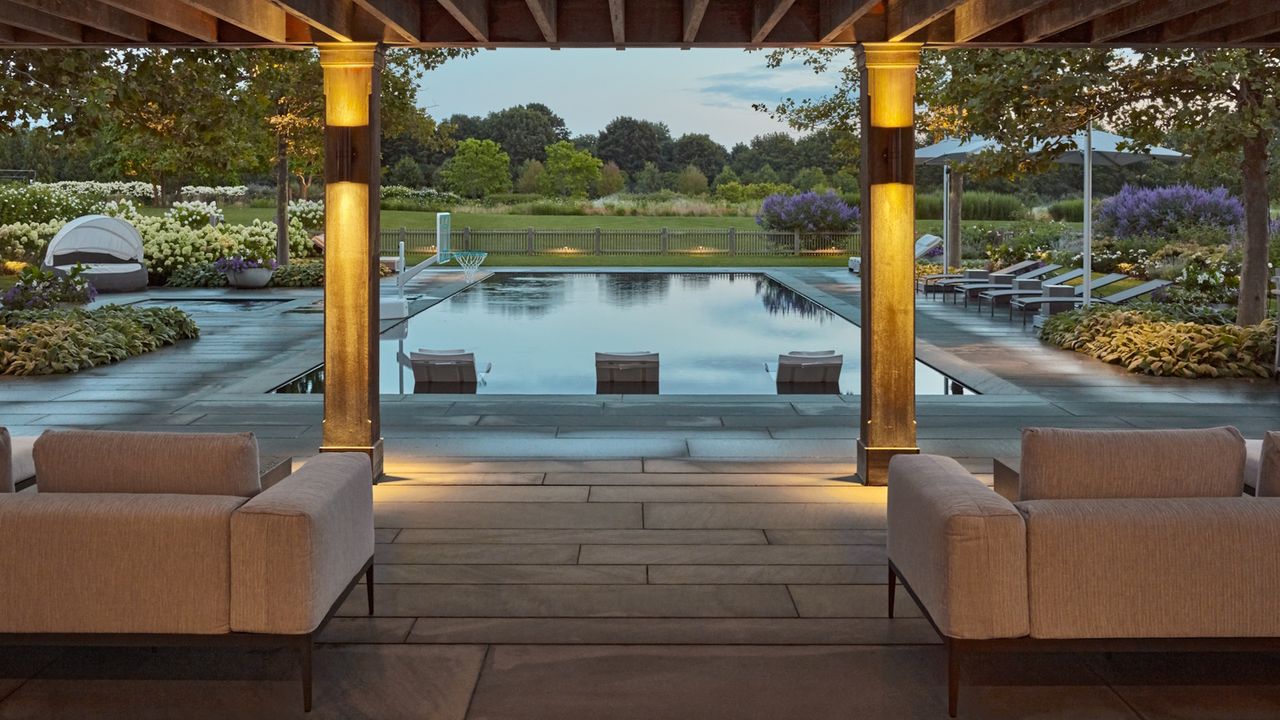 Modern patio with view of a large swimming pool and trees