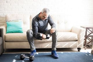 Man performs single-arm concentration curl at home