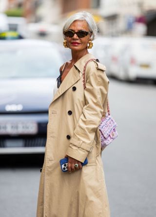 Grece Ghanem wears beige trench coat, pink Chanel bag, Chanel sandals outside Gestuz during day four of the Copenhagen Fashion Week