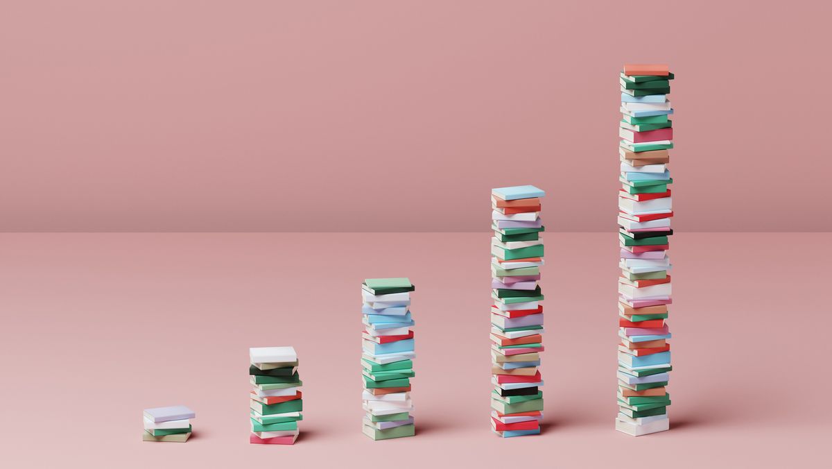 A digital image showing books stacked up in five increasingly large piles to resemble a graph. Decorative: the spines of the books are all different colours and they are set against a pink floor and wall.