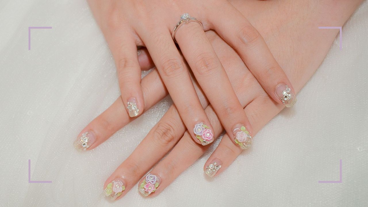 A floral nail art wedding nail design shown on bride&#039;s hands