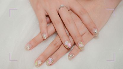 A floral nail art wedding nail design shown on bride's hands